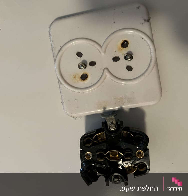 שקע חשמלי מפורק עם ברגים וחלקים פנימיים חשופים